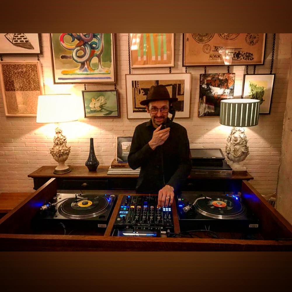 Sesión con dos platos de vinilo en una sala con cuadros en la pared