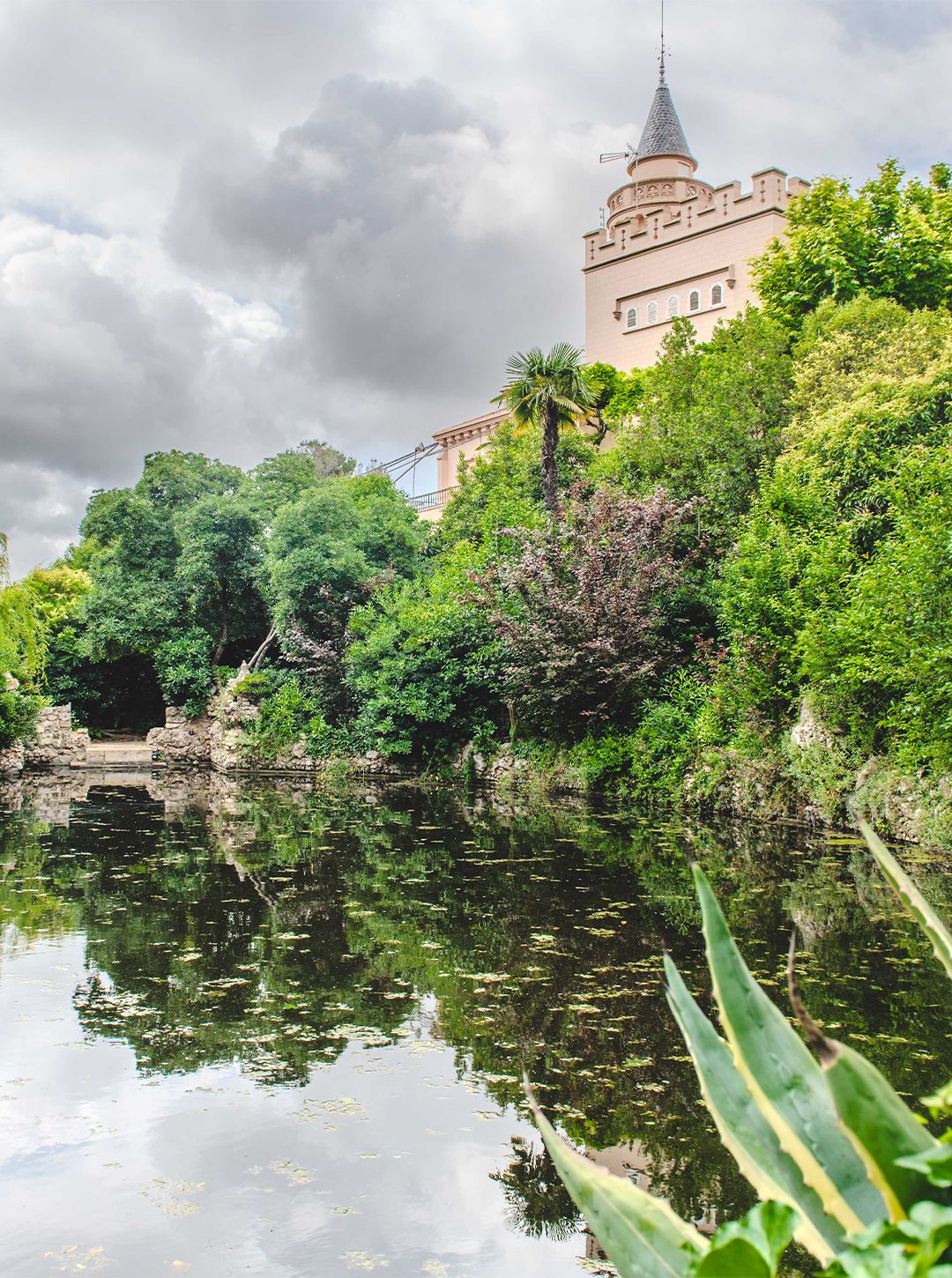 The modernist tower at Bellesguart above the pond, among the greenery