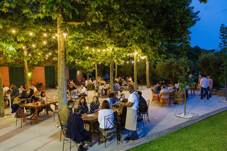 The garden at La Torre del Gall at night, with tables under the trees and string lights