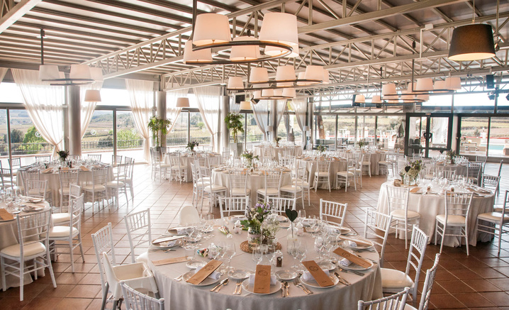 Banquet hall at Masia Torreblanca with round tables and windows onto the countryside